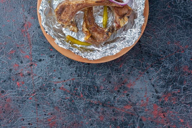 Costelas de cordeiro grelhadas colocadas sobre uma mesa escura.