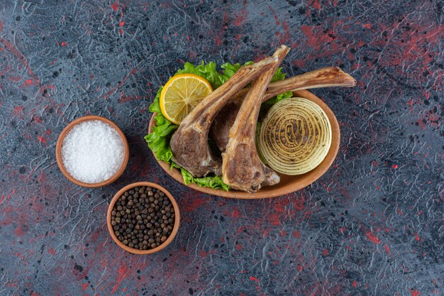 Costelas de cordeiro grelhadas com especiarias colocadas sobre uma mesa escura.