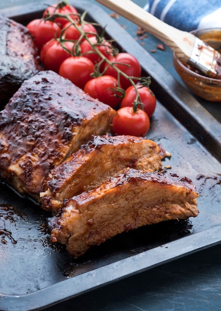 Costelas de porco grelhadas com tomates cereja assados em uma bandeja. Carne assada