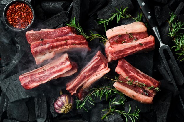 Foto costelas de vitela cruas frescas com romário em carvões preparação de carne churrasco espaço livre para texto