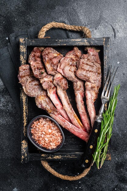 Costeleta de carne de carneiro bife de costeleta de cordeiro grelhada em bandeja de madeira Fundo preto Vista superior