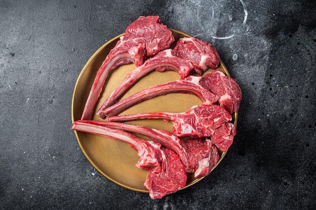 Costeleta de carne de carneiro cru bife de costela de cordeiro em chapa dourada Fundo preto Vista superior