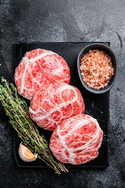 Costeletas cruas de Atriaux carne de porco moída envolta em salsicha suíça de gordura Fundo preto Vista superior