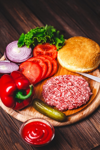 Costeletas de bife de hambúrguer com tempero, queijo, tomate, salada e pão em tábuas de madeira vintage