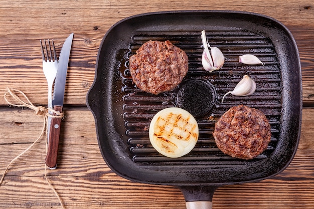 Costeletas de carne de hambúrguer frito com cebola e alho