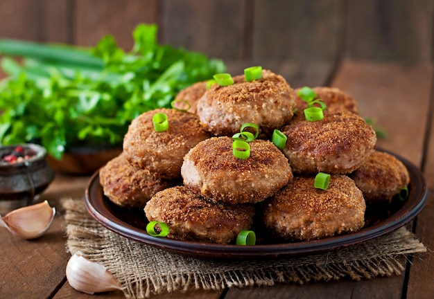 Foto costeletas de carne deliciosa suculenta em uma mesa de madeira em estilo rústico.