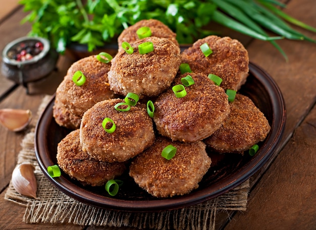 Costeletas de carne deliciosa suculenta em uma mesa de madeira em estilo rústico.