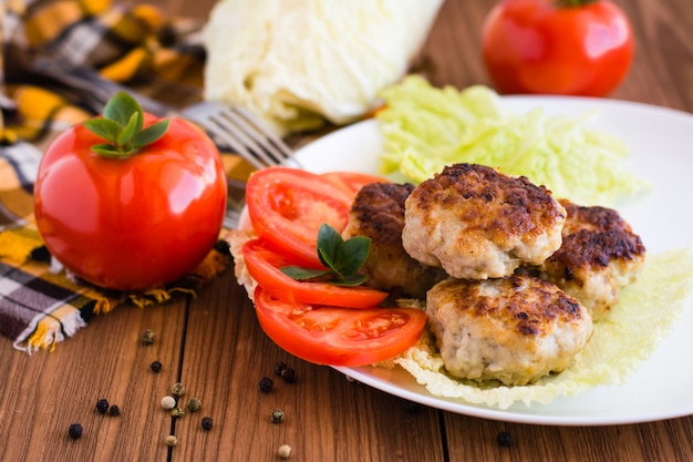 Costeletas de carne e legumes frescos em uma mesa de madeira