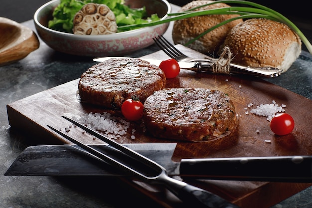 Foto costeletas de hambúrguer com carne crua de carne moída com ingredientes no tabuleiro