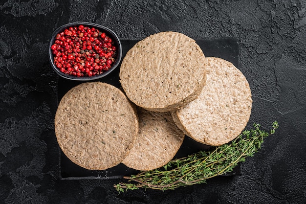 Costeletas de hambúrgueres não cozidas feitas de carne vegetal crua rissóis veganos Fundo preto Vista superior