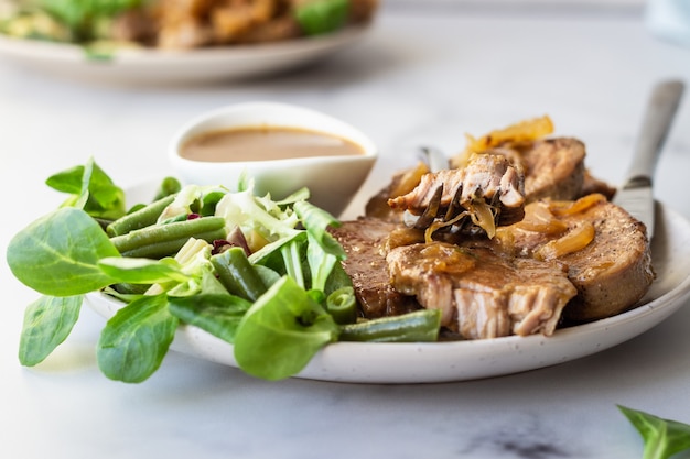 Costeletas de porco suculentas fritas com cebola caramelizada e molho servido com salada verde e feijão