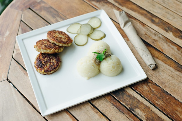 Costeletas vegetarianas com purê de batatas e picles na mesa de madeira