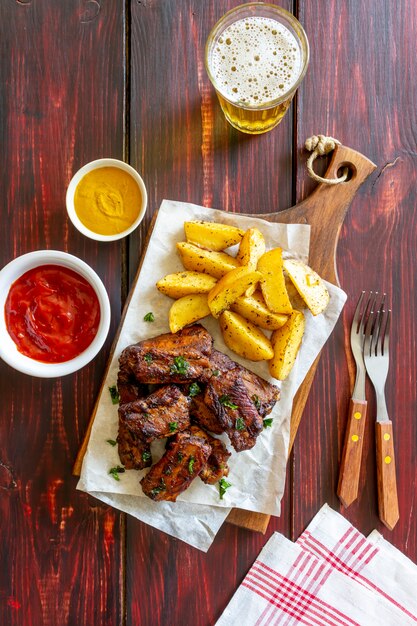 Costelinha de porco com batatas em uma mesa de madeira. Churrasco. Grade. Cozinha americana. Receita.