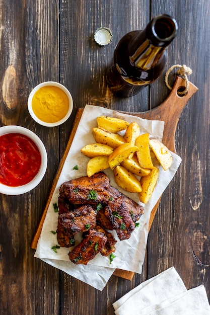 Costelinha de porco com batatas em uma mesa de madeira. Churrasco. Grade. Cozinha americana. Receita.