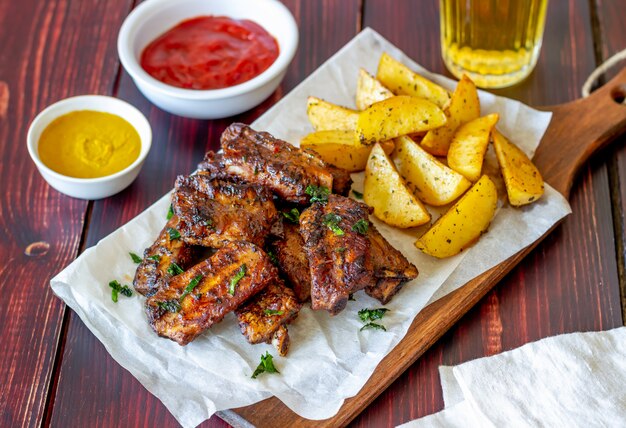 Costelinha de porco com batatas em uma mesa de madeira. Churrasco. Grade. Cozinha americana. Receita.