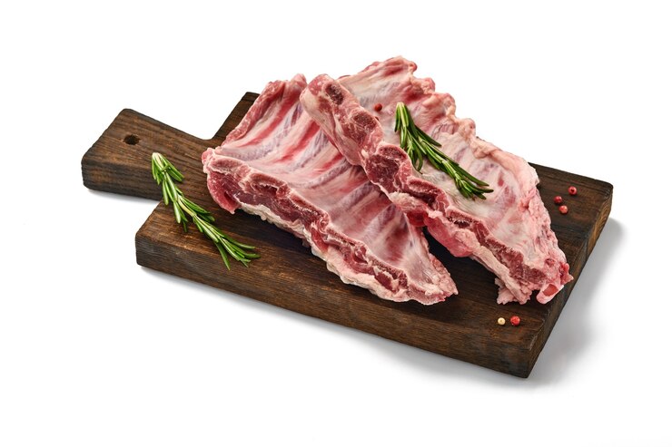Costelinha de porco crua com alecrim e pimenta vermelha, isolado no fundo branco. Carne crua. Foco seletivo.