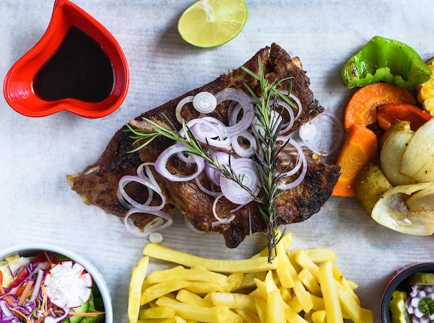 Costelinha de porco defumada grelhada com batatas fritas e molho de soja e salada na tábua de madeira