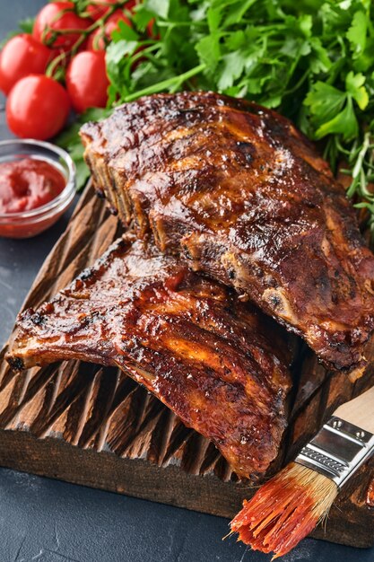 Costelinha de porco grelhada e defumada com molho de churrasco em uma velha tábua de madeira vintage. Lanche saboroso para cerveja. Imagem do close up.