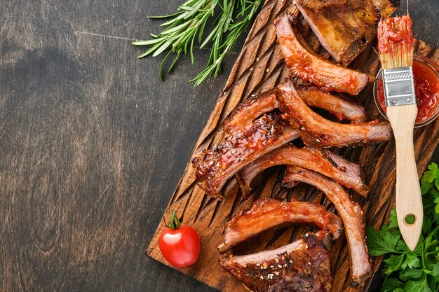 Costelinha de porco grelhada e defumada com molho de churrasco em uma velha tábua de madeira vintage. Lanche saboroso para cerveja. Imagem do close up.