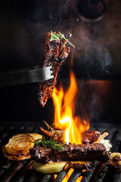 Costelinha de porco grelhada na grelha picada no garfo contra o fogo