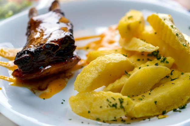 costilla y carne a la barbacoa con patatas fritas y ensalada