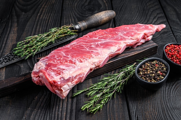 Costilla de cerdo de ternera cruda con cuchillo de carnicero.