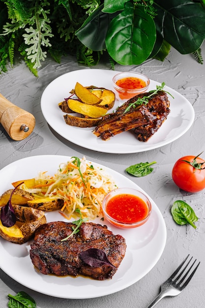 Foto costillas de barbacoa con guarnición en platos elegantes