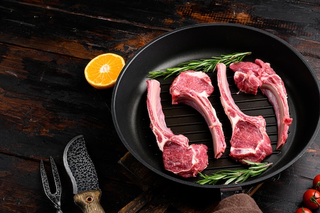 Costillas de carne fresca cruda colocadas en una sartén de hierro fundido sobre un fondo de mesa rústico oscuro antiguo