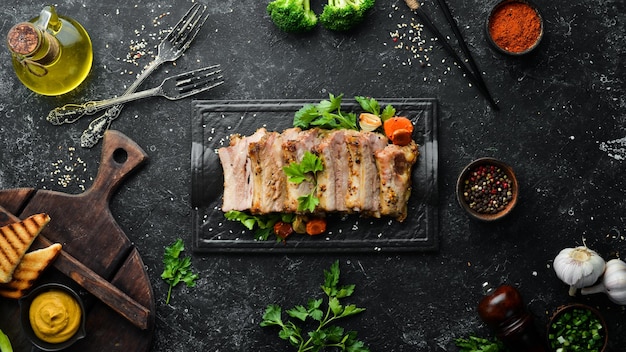 Costillas de cerdo al horno con mostaza y especias en un plato de piedra negra Vista superior Espacio libre para texto