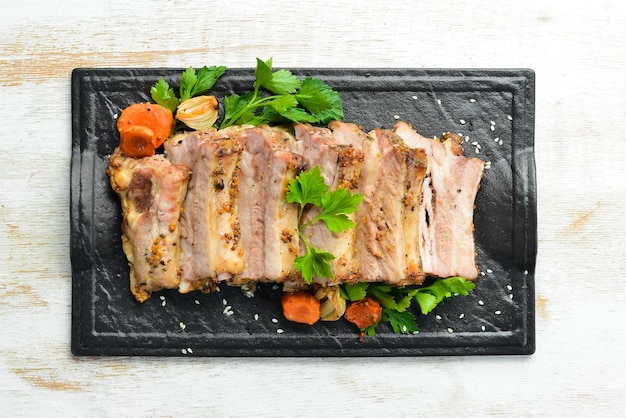 Costillas de cerdo al horno con mostaza y especias en un plato de piedra negra Vista superior Espacio libre para texto