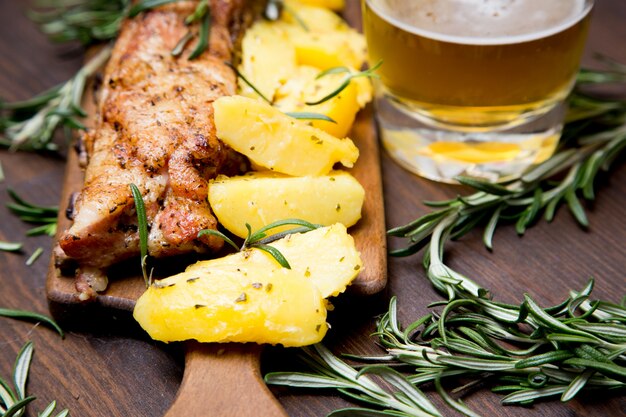 Costillas de cerdo al horno con papas, romero y un vaso de cerveza.