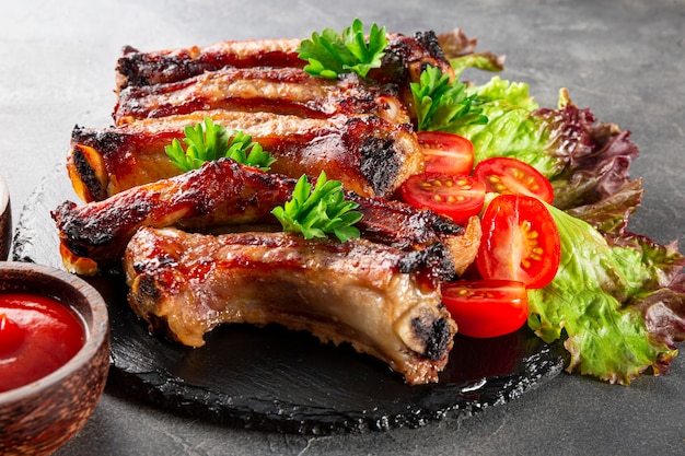 Costillas de cerdo al horno con verduras mostaza y salsa de tomate sobre fondo gris cerrar