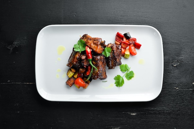 Costillas de cerdo al horno con verduras En el plato Sobre un fondo de madera Vista superior Espacio libre para el texto