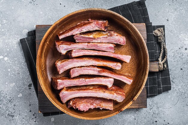 Costillas de cerdo asadas ahumadas caseras en plato de madera listas para comer Fondo gris Vista superior