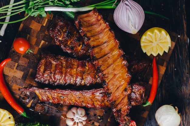 costillas de cerdo asadas en un ahumador de pie en una tabla de cortar adornadas con chile de pimienta de romero