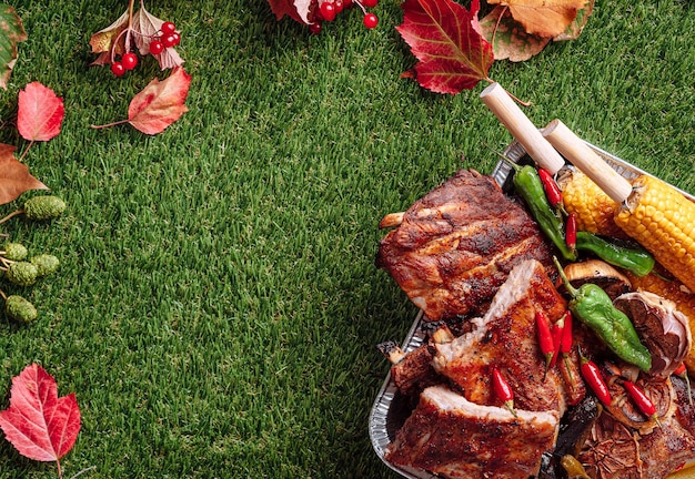 Costillas de cerdo asadas a la barbacoa de otoño, maíz y pimientos asados, ajo horneado, concepto de fiesta a la parrilla de otoño, Día de Acción de Gracias, cosecha de otoño