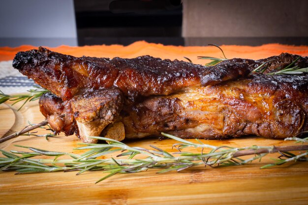 Costillas de cerdo asadas con salsa barbacoa de romero en un tablero de madera para texto