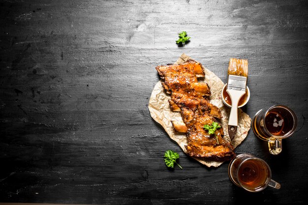 Costillas de cerdo a la barbacoa con cerveza y salsa en la pizarra negra