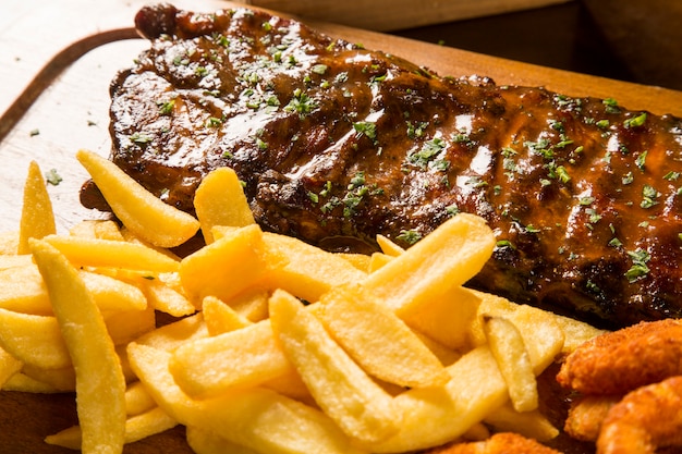 Costillas de cerdo a la barbacoa con papas fritas y aros de cebolla