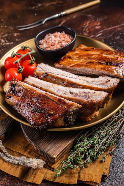 Costillas de cerdo a la barbacoa picadas en un plato con hierbas Fondo oscuro Vista superior