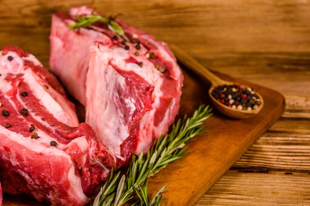 Costillas de cerdo crudas con especias y romero sobre una tabla para cortar