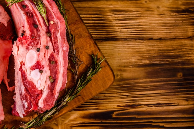 Costillas de cerdo crudas con especias y romero en una tabla para cortar. Vista superior