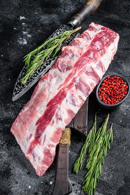 Costillas de cerdo crudas frescas con especias en una tabla para cortar con un cuchillo.