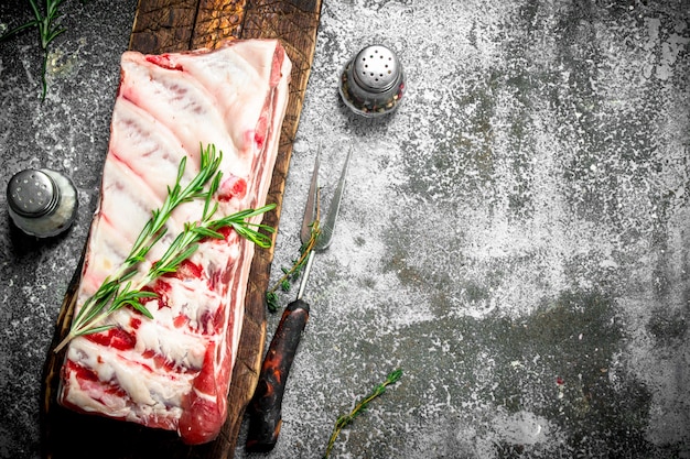 Costillas de cerdo crudas con hierbas y especias. Sobre fondo rústico.