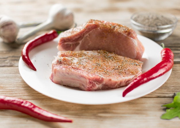 Costillas de cerdo crudas con pimiento rojo, ajo y condimentos sobre un fondo de madera