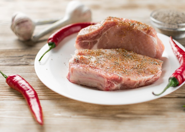 Costillas de cerdo crudas con pimiento rojo, ajo y condimentos sobre un fondo de madera