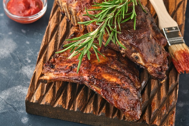 Costillas de cerdo a la parrilla y ahumadas con salsa barbacoa sobre una vieja tabla de cortar de madera vintage. Aperitivo sabroso a cerveza. Imagen de primer plano.