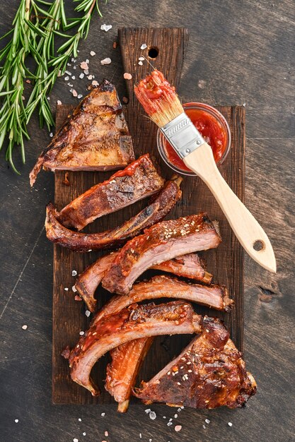 Costillas de cerdo a la parrilla y ahumadas con salsa barbacoa sobre una vieja tabla de cortar de madera vintage. Aperitivo sabroso a cerveza. Imagen de primer plano.