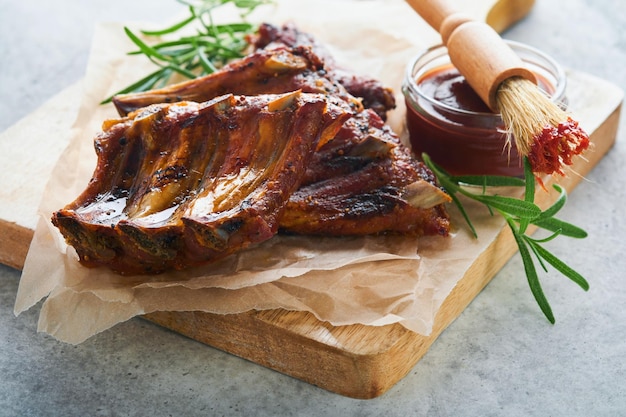 Costillas de cerdo a la parrilla y ahumadas con salsa de barbacoa en una vieja tabla de cortar de madera vintage sobre fondo de mesa de madera vieja Sabroso bocadillo para cerveza Concepto de comida americana Vista superior