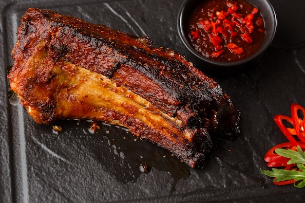 Costillas de cerdo a la parrilla y asadas con guindilla y salsa picante sobre piedra negra